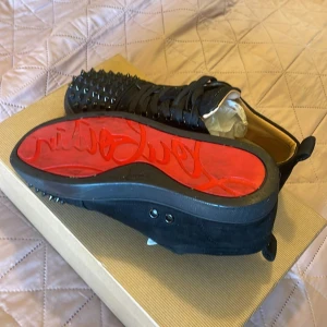 Svarta sneakers med nitar från Christian Louboutin - Säljer ett par svarta sneakers från Christian Louboutin. Priset kan diskuteras. De har en cool design med nitar på ovansidan och den ikoniska röda sulan. Skorna är i nyskick och kommer med originalkvitto och äkthetsbevis. Gör din outfit till en 10/10!