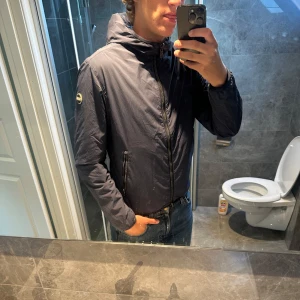 Mörkblå vindjacka från Colmar - Riktigt fet Colmar vindjacka i storlek 50 som motsvarar S/M. Jag är 188cm och den är något liten på mig. Jackan går även att vända ut och in och blir då till en ljusblå färg som man ser i luvan. Jackan har inga defekter och är i riktigt bra skick. Nypris ca 2000kr.      Bara att höra av sig om man har några frågor;)