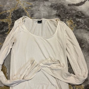 Vit långärmad tröja Gina Tricot - En enkel och mjuk vit långärmad tröja från Gina Tricot i storlek S. Tröjan har rundad halsringning och är tillverkad i ett tunt bomullsmaterial som känns skönt mot huden. Perfekt att styla med jeans eller kjol för en clean look.