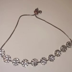 Glittrigt silverfärgat armband - Snyggt armband i silverfärg med glittrande runda dekorationer som ser ut som små blommor. Justerbar kedja med pärldetalj vid låset. Perfekt för dig som gillar att sticka ut med lite extra bling.