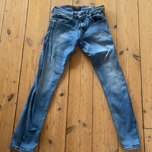 Replay Grover jeans blå 30/32 - Snygga Replay Grover jeans i klassisk blå tvätt med coola slitningar och raka ben. Jeansen har fem fickor, knappgylf och tydliga Replay-detaljer på bakfickan och midjan. Perfekt passform för dig som gillar en modern och avslappnad stil.