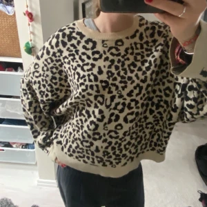 Stickad Leo tröja  Gina Tricot - Säljer en beige stickad tröja från Gina Tricot med svart leopardmönster. Tröjan har rund hals, lång ärm och en loose passform som ger en chill vibe. Väldigt mjuk 