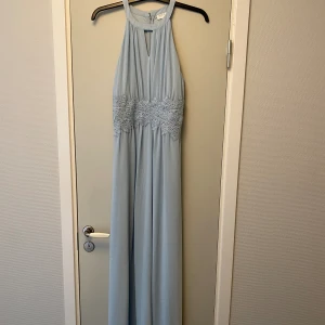 Långklänning Vila - Långklänning i ljusblått från Vila. Bra skick men med fläckar längst ned på kjolen (se bild). Syns inte så tydligt och kankse går att få bort, jag jag inte aktivt försökt. Katt finns i hemmet. 