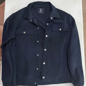 Marinblå jacka/overshirt - Storlek M, säljer denna overshirt då den används nästan aldrig. Passar riktigt bra som en jacka för våren.