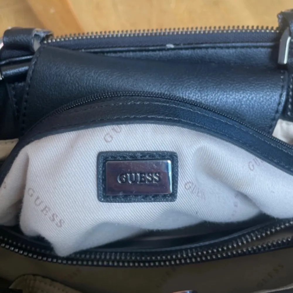En svart handväska från guess. Många bra fack med beige insida. Handtagen är slitna. Pris kan diskuteras. #guess #handväska #dam #vintage. Väskor.