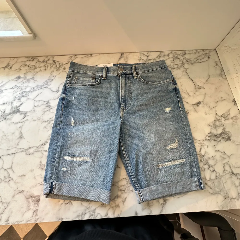Ett par helt nya riva mörkblå jeansshorts. Shortsen är tunga men mjuka och sitter perfekt på kroppen. De har passformen slim fit och är tillräckligt luftiga för att spendera en hel sommar i de. Fick de i present av en släkting. . Shorts.
