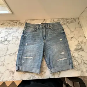 Ett par helt nya riva mörkblå jeansshorts. Shortsen är tunga men mjuka och sitter perfekt på kroppen. De har passformen slim fit och är tillräckligt luftiga för att spendera en hel sommar i de. Fick de i present av en släkting. 