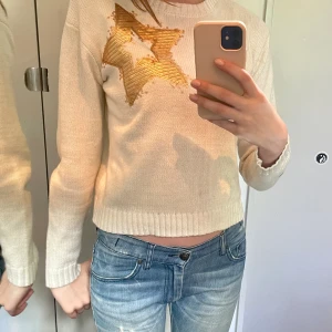 Vit Stickad Tröja med Stjärnor - Supersnygg stickad tröja med guldiga stjärnor. Perfekt längd och i jättebra skick!💕Egentligen en barntröja i Large, men passar bra för XS och S. Däremot kan den vara lite kort i ärmarna om man har längre armar!