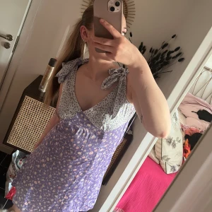 Blommig klänning - SÅ fin sommarklänning!! Glansigt material, blommig, du knyter banden själv, fin och smickrande passform vid bysten. Köpt för ca 2 år sedan. Lite för kort för min smak därav aldrig använd & har lapp kvar🩷