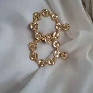 Roliga örhängen som är guldfärgade och täckta av små fake-diamanter. Örhängena är även i någon slags metall