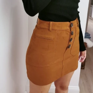 ZARA kjol stl XS/S nyskick - Jättefin brun kjol från Zara. Mocka liknande material. Storlek: XS. Jag är storlek S och på bilderna ser ni hur det ser ut på mig. Helt nyskick.