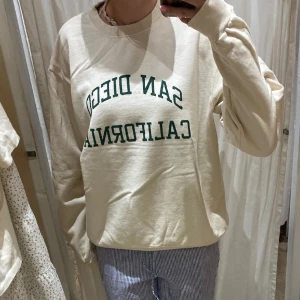 Brandy Melville top  - En fin crewneck/sweatshirt med tryck från Brandy Melville. Köpt i somras men aldrig använd. Helt fri från fläckar, är inte helt vit utan väldigt ljusbeige. Köpt för ca 450kr