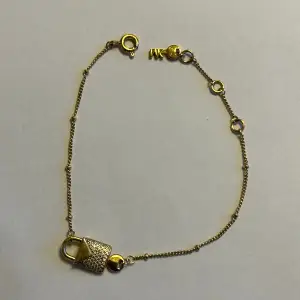 Armband från Michael Kors, guldpläteringen har skavts av på smådelar av berlocken (se bild 2), utöver det är det i bra skick!  Mått: 18,5 cm (max), 15,5 cm (min). Justerbar fästning.  Ordinariepris: 2 195kr  
