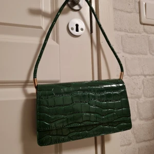 Handväska - Helt ny oanvänd väska i krokodilmönstrad design. Kom tyvärr inte till användning. Kartongpappren inuti väskan är kvar med. 