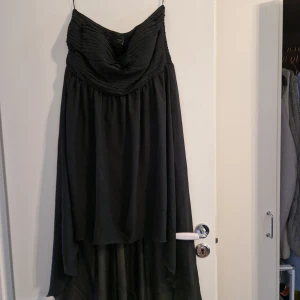 Axelbandslös klänning  - Klänning utan axelband. Längre i bak som ett litet "släp".