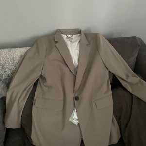 Ny kavaj - Helt ny kavaj ifrån hm. Storlek m. Jättesnygg. Färgen är grå/grön skulle jag säga. 300 kr 