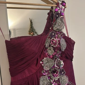 Magenta klänning  - Lång magenta klänning med silver,grå och magenta strass samt blommor.  Den är väldigt vintage och har många lager så det är därför den ser konstigt ut på bilden. Den är unik eftersom den är från Syrien innan kriget började. Ungefär 15 år gammal.
