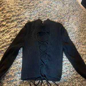 Ribbad tröja med knuten rygg  - Jätte fin svart ribbad tröja, som knyts i ryggen. Använt 1 gång