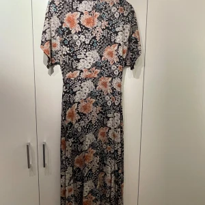 Klänning  - Snygg klänning i viskos/bomull hög hals, snygg knäppning baktill. Markerande midja, längd strax under knä. 