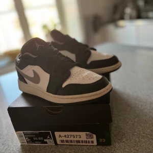 JORDAN 1 ” BLACK WHITEBOARDEN GREY” LOW,  - Säljer mina snygga jordan 1 low skor för de är för små. Snygga och sköna inför sommaren och är köpta från stockx och har dessutom verifieringsmarkör. I boxen ingår det  ett par jordans i väldigt bra skick en jordan sticker. användna 5-10 gånger