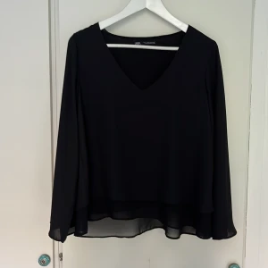 Zara snygg svart blus strl S - Superfin, knappt använd långärmad svart blus från Zara. Skir effekt med tunt, följsamt tyg i två lager.