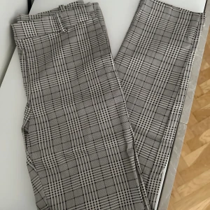 Kostymbyxor från H&M - Rutiga kostymbyxor från H&M, sitter skit bra på, stretchiga i materialet. Stängs på sidan med knapp o dragkedja, liten slits vid sidan av benet. Kommer dock inte till användning, är precis som nya.
