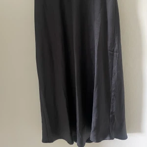 Svart Midi kjol - Svart midi kjol i satin liknande material från Vila i storlek 36. 