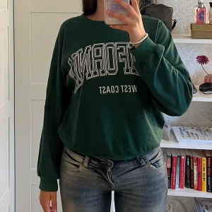 Grön långärmad tröja - Grön långärmad tröja med tryck. Tryck: ”CALIFORNIA west coast”  Storlek 36