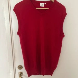 Röd väst från boomerang  - Finstickad väst från märket boomerang i storlek L. Västen har lagats vid ena axeln så som syns på bilden. Den har annars inga hål osv. 