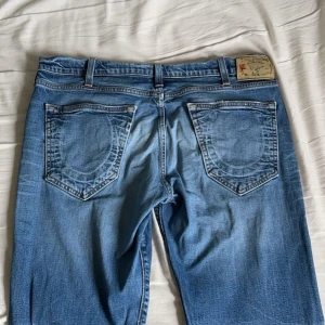 True Religion Blåa Jeans - Köpt från sellpy förra året för ca 700kr. Jag säljer jeansen eftersom jag har tröttnat på dem. Skicket är helt okej, de är använda men det finns inget tydligt problem. Det är INTE skinny men heller inte jätte baggy. Kontakta mig om du har en fråga :)