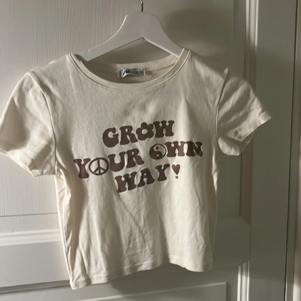 Beige croppad t-shirt med brun text. . T-shirts.