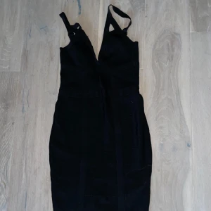 Svart klänning med dragkedja - En elegant svart bandage klänning med dragkedja. Klänningen har en tight passform och är ärmlös med smala axelband. Den har en stilren design och är perfekt för festliga tillfällen.