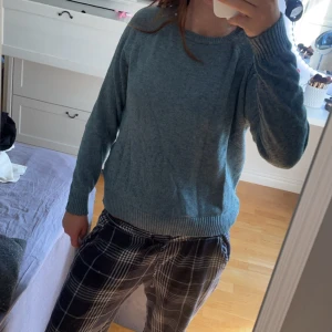 Grå stickad tröja - En bekväm turkos aktig stickad tröja med långa ärmar och ribbstickade muddar vid ärmslut och nederkant.