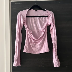 Ginatricot topp - Söt rosa topp med långa ärmar och en unik design. Toppen är figursydd och har en avslappnad passform. Perfekt för att klä upp en vardaglig outfit eller för en kväll ute.