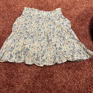 Fin volangkjol med blommigt mönster - Fin vit kjol med vita och blåa blommor Lite volanger och i storlek M/38❤️❤️