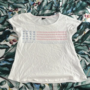  Vit t-shirt  -  En jättefin vit t-shirt från Gina Tricot med ett märke av USA flaggan fast med rosa och blå 💕💕