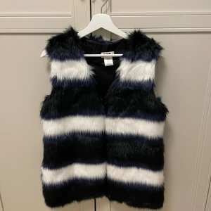 Väst - Fuskpäls, färgerna är vit, svart och blå. 