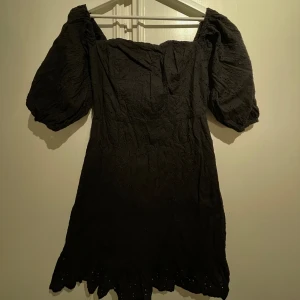 Klänning - Somrig minidress med puffärmar, broderat blomstermönster(bild 2) och volangdetaljer längs skärningen på kjolen. Använd men i mycket fint skick.