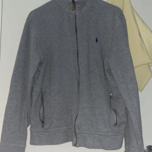 Polo zip hoodie  - Säljer min gråa polo zip! Storlek L! Använd ett antal gånger! Har ganska bra skick! Priset kan diskuteras! Inga byten! 