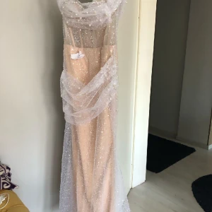 Helt ny kläning utan användning - Beige kläning med glitter och pärla på. Har en slät som ingår med kläningen st 38/40