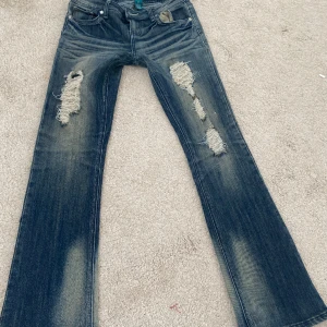 Super lågmidjade vintage y2k jeans bootcut - Från ”almost famous”. Midjemått: 38 cm. Innerben: 79cm. Satt lite tight på mig när jag fick hem dom därav säljer jag. Vintage med fint skick(många slitningar på framsidan av benen men de är en del av modellen). Tryck gärna på köp nu eller prisförslag