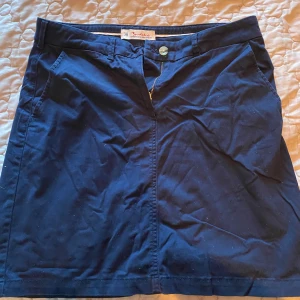 Bondelid kjol - Marinblå Bondelid kjol Knäppning med knapp och dragkedja 2 fickor på sidorna  Använd ca 5ggr Storlek 38 Rök och djurfritt hem