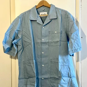 Kortärmad skjorta Seidensticker Studio, ljusblå, XL - Ser lite ut som denim men är mycket mjukare. Tre fickor, öppen krage, lös passform. Oanvänd och lite skrynklig från förvaring.