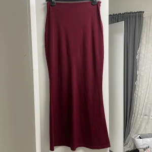 Vinröd lång kjol - Lång vinröd kjol helt oanvänd, säljer p.g.a att jag inte kan lämna tillbaka den. Den har en stretchig material vilket gör att den sitter som ett smäck, verkligen fin och elegant kjol. Köptes för 250kr säljer för 100kr.