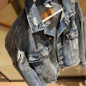”Croppad” jeansjacka med slitningar, storlek S men sitter oversized