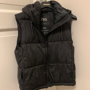 Svart väst från Zara - Säljer denna svarta västen från Zara då jag inte använder den längre! Tror inte den finns i butik längre, köpte den för kanske 2-3 år sen. Den är iaf superskön och har luva + högre krage! Den är i bra skick, kom privat för mer info ☺️ 