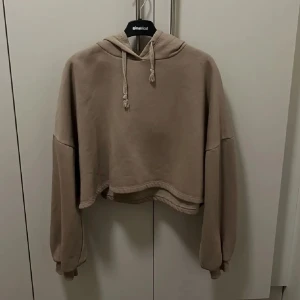 Beige Croppad Hoodie - Ginatricot - Beige croppad hoodie, supercozy och gullig, bra material, från Ginatricot. Köpt för 299kr säljer för endast 99kr! 