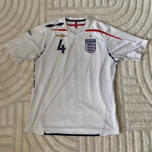 ENGLAND FOTBOLLSTRÖJA  - ORIGINAL ENGLAND HEMMA/ 2007-2009 Steven Gerrard #4   STORLEK: L PRIS: 499 SEK   OBS! Produkten stryks innan den fraktas iväg. Vid köp eller funderingar kontakta oss.   Instagram: @beyondthekits EJ REPLIKA #england#umbro#gerrard