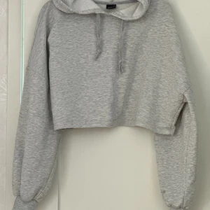 Grå croppad hoodie  - Grå croppad hoodie i storlek S från Gina Tricot🦭 På den vänstra ärmen finns det en svart fläck som är ungefär 2cm stor. Färgen smälter dock in i tröjan ganska bra eftersom att tyget består av olika gråa nyanser. För övrigt är tröjan i bra skick! 
