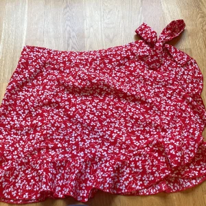 Röd blommig kjol ❣️💌 - Blommig röd kjol med rosett och volanger längst kjolen. 